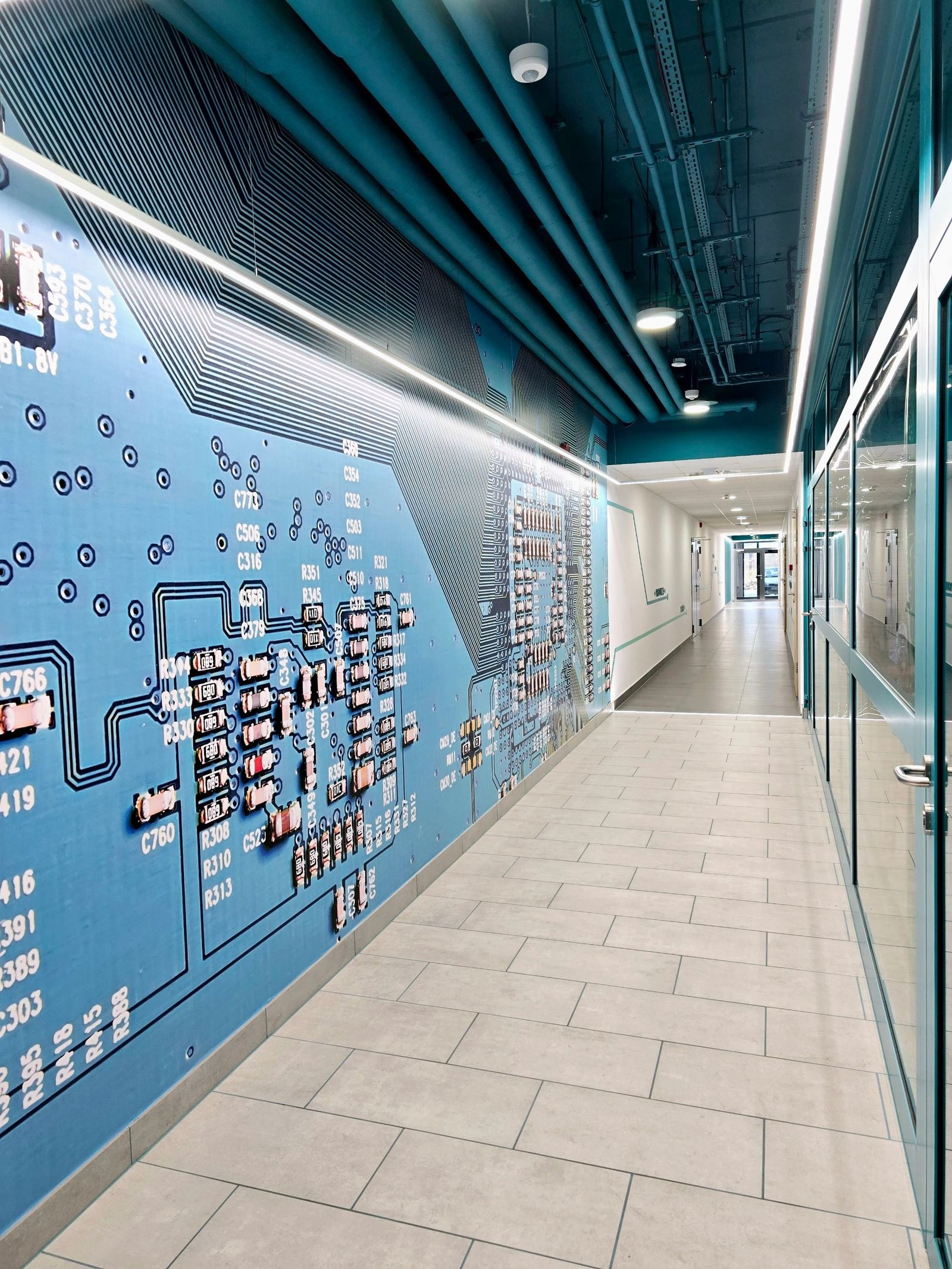 Ściana z wielkoformatową grafiką płytki drukowanej i linia światła LED biegnąca wzdłuż korytarza